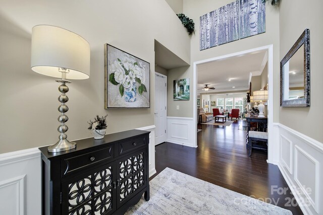 entrance foyer featuring dark wood finished floors, a decorative wall, a wainscoted wall, and ceiling fan