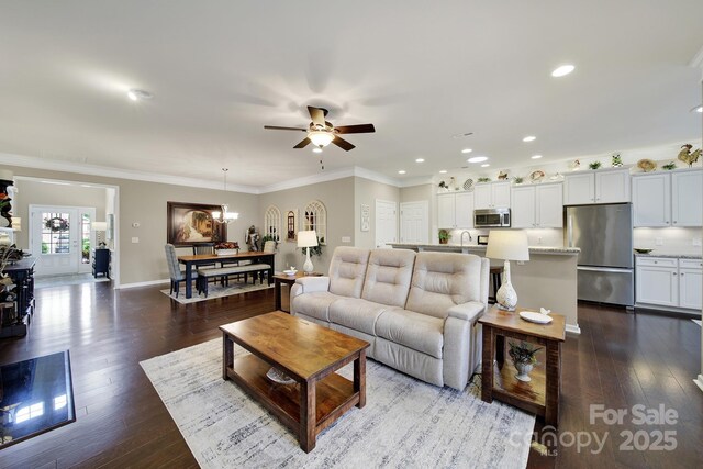 living area with dark wood-style floors, baseboards, recessed lighting, ceiling fan, and ornamental molding