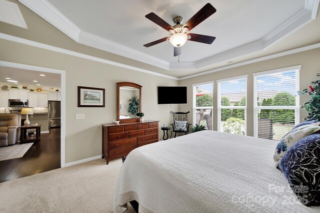 bedroom with crown molding, a tray ceiling, and freestanding refrigerator