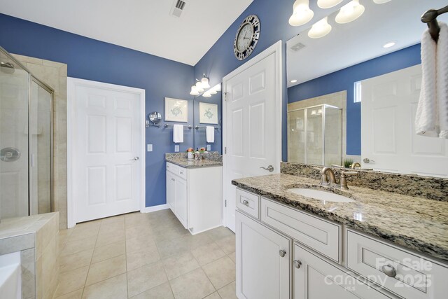 bathroom with a shower stall, tile patterned floors, visible vents, a sink, and two vanities