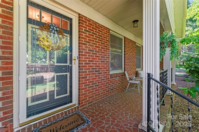 entrance to property with covered porch and brick siding
