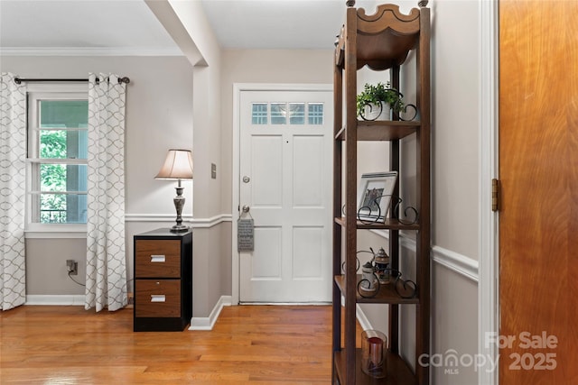 foyer featuring light wood-style floors, crown molding, and baseboards