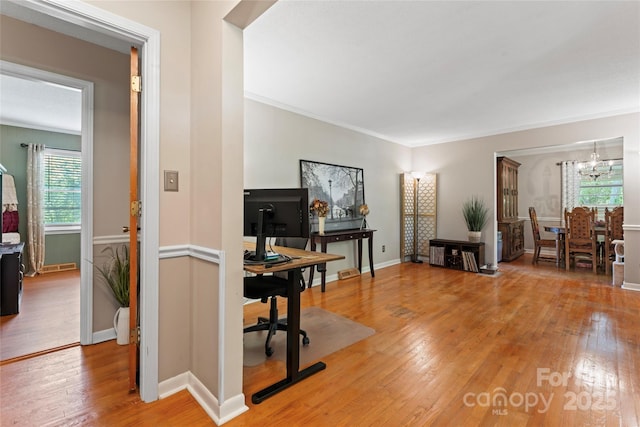 interior space with light wood finished floors, baseboards, an inviting chandelier, and ornamental molding