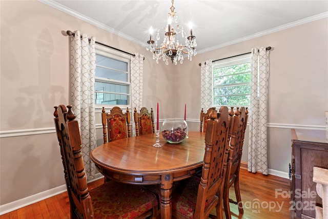 dining area featuring baseboards, wood finished floors, a chandelier, and crown molding