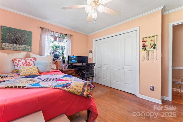 bedroom with wood finished floors, a ceiling fan, a closet, crown molding, and baseboards