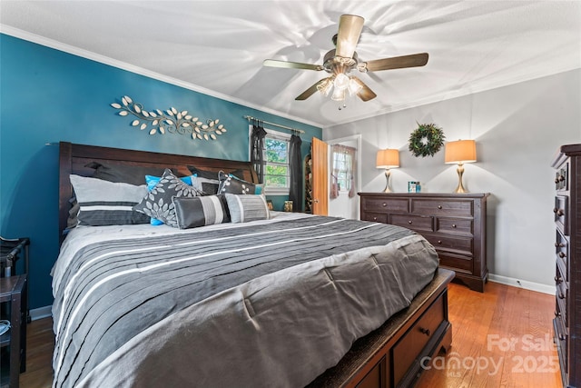 bedroom featuring baseboards, a ceiling fan, wood finished floors, and crown molding