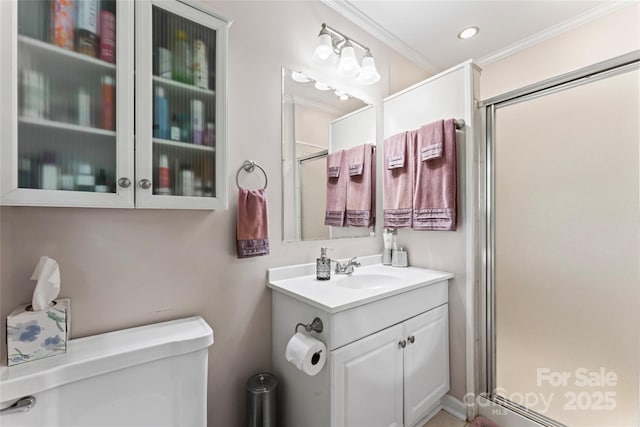 bathroom with toilet, vanity, a shower stall, and crown molding