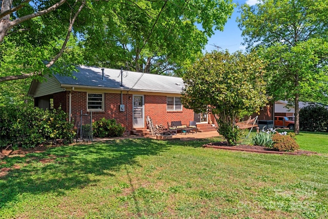 back of property with a lawn, entry steps, brick siding, and a patio