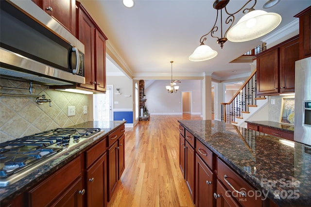 kitchen with light wood-type flooring, baseboards, backsplash, appliances with stainless steel finishes, and ornamental molding