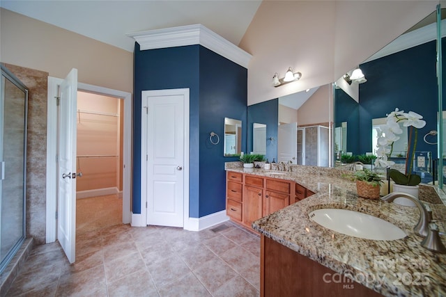 bathroom featuring tile patterned floors, baseboards, a spacious closet, a shower stall, and vanity