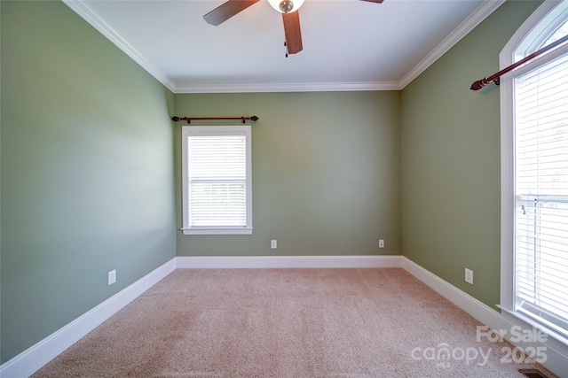 carpeted empty room featuring a ceiling fan, baseboards, and crown molding