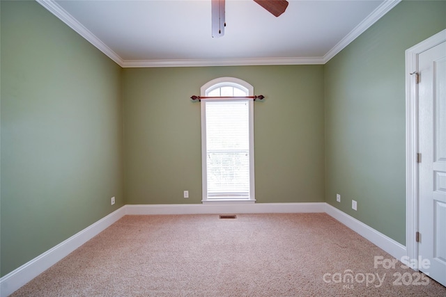 carpeted spare room with a ceiling fan, baseboards, crown molding, and visible vents
