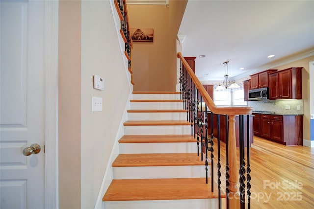 stairs with recessed lighting, a chandelier, wood finished floors, and crown molding