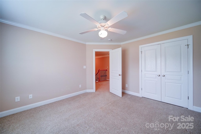 unfurnished bedroom with carpet, a closet, crown molding, and baseboards