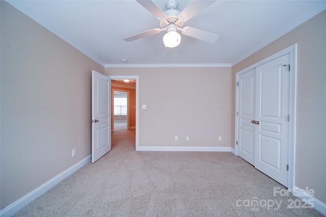 unfurnished bedroom featuring ceiling fan, carpet floors, baseboards, and ornamental molding