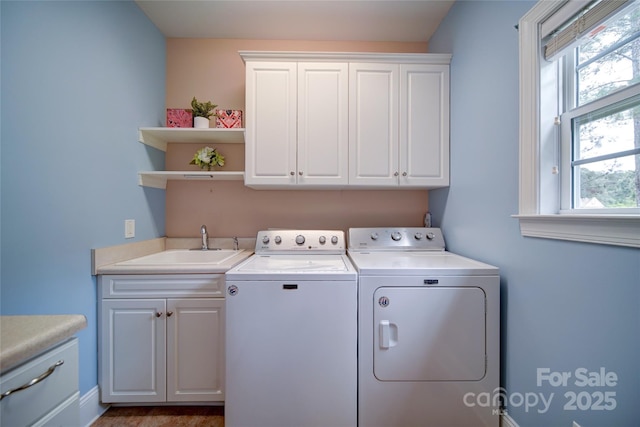laundry area with cabinet space, independent washer and dryer, and a sink