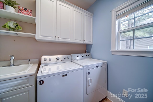 laundry area featuring separate washer and dryer, a sink, and cabinet space