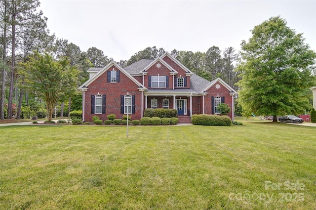 view of front facade with brick siding, a porch, and a front yard