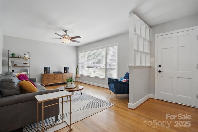 living room featuring light wood-type flooring, a ceiling fan, and baseboards