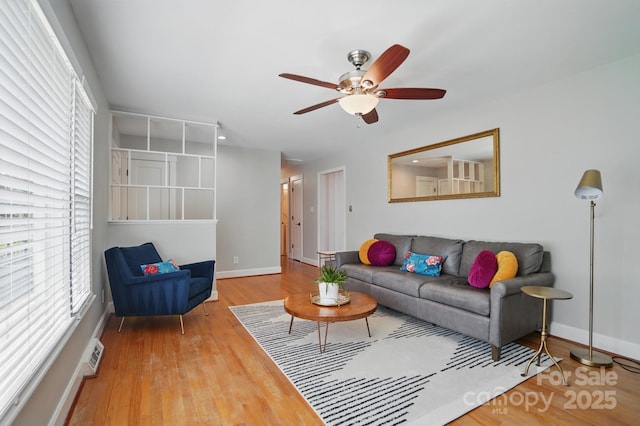 living area featuring wood finished floors, visible vents, baseboards, and ceiling fan