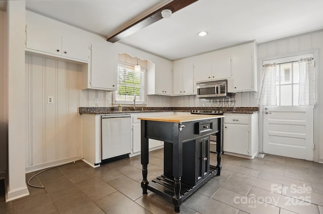 kitchen with white cabinets, stainless steel appliances, tile patterned floors, wood counters, and a kitchen island