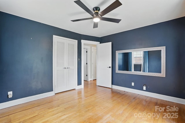 unfurnished bedroom with wood finished floors, baseboards, a closet, and ceiling fan