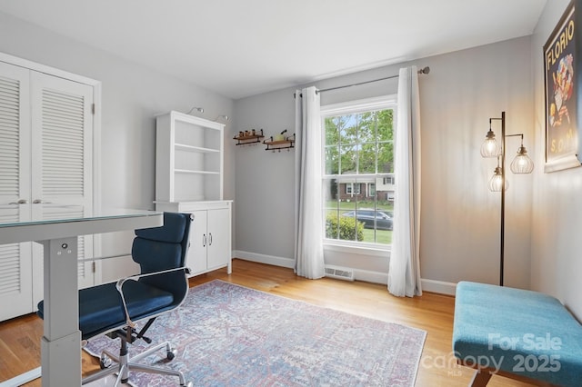 office space with baseboards, wood finished floors, and visible vents