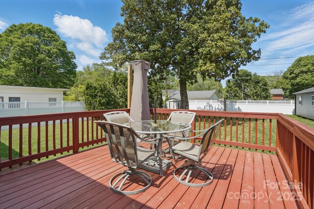 wooden deck with a fenced backyard, a yard, and outdoor dining space