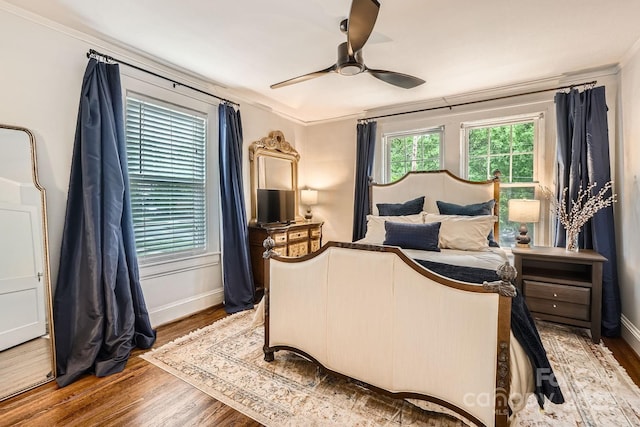 bedroom with baseboards, wood finished floors, a ceiling fan, and crown molding