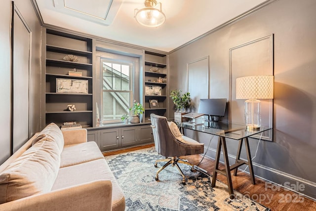 office with wood finished floors, crown molding, built in features, and baseboards