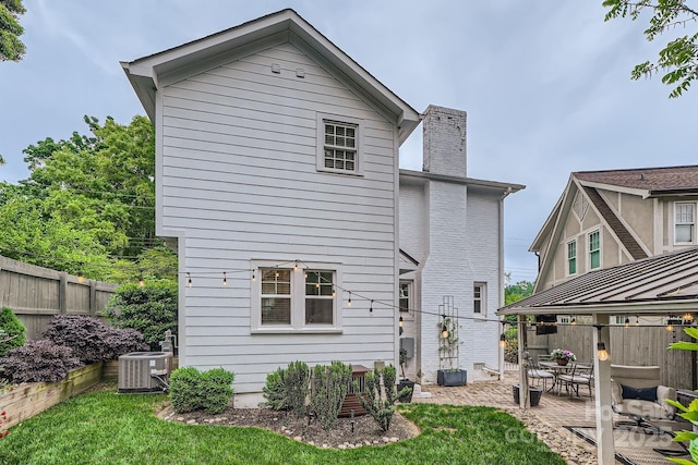 rear view of property featuring a chimney, a fenced backyard, central AC unit, and a patio area