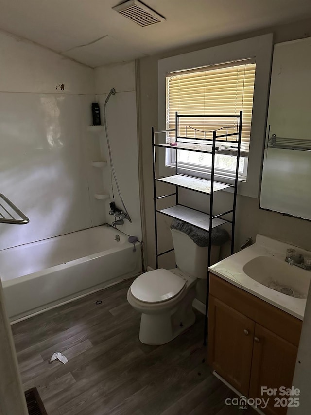 bathroom featuring wood finished floors, vanity, toilet, visible vents, and bathing tub / shower combination