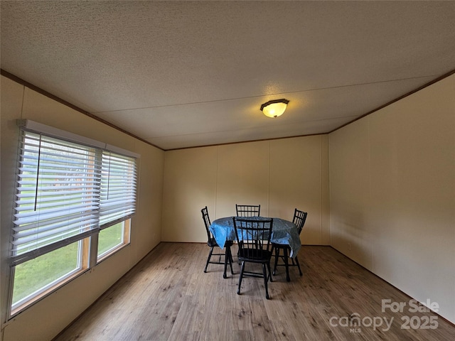 dining area featuring a textured ceiling, ornamental molding, and light wood finished floors