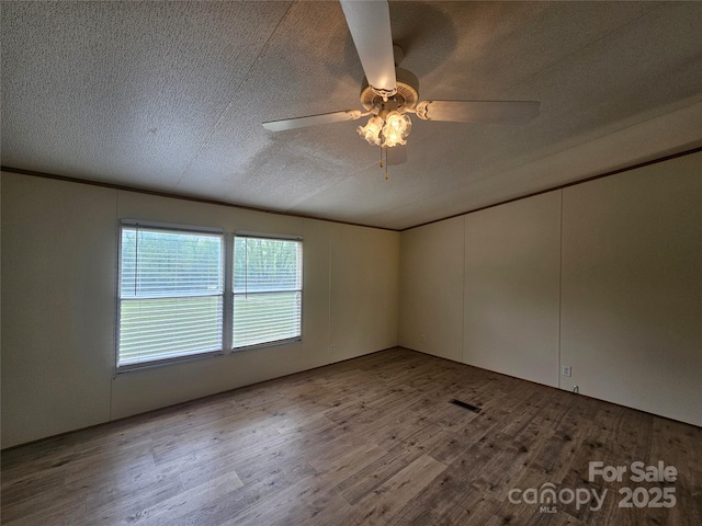 unfurnished room with visible vents, a ceiling fan, a textured ceiling, and wood finished floors