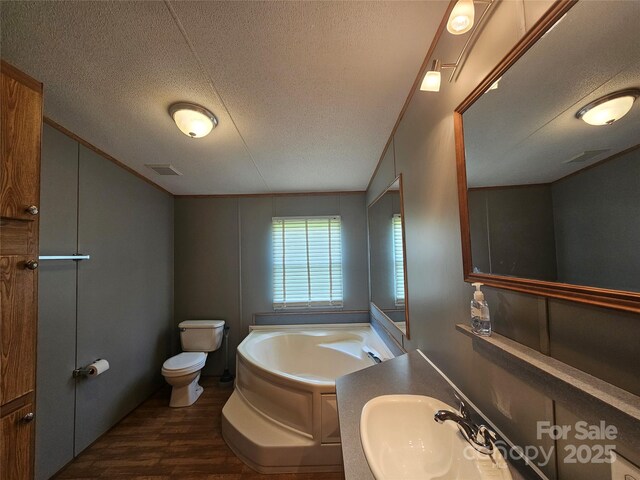 full bath featuring a garden tub, a textured ceiling, visible vents, wood finished floors, and a sink