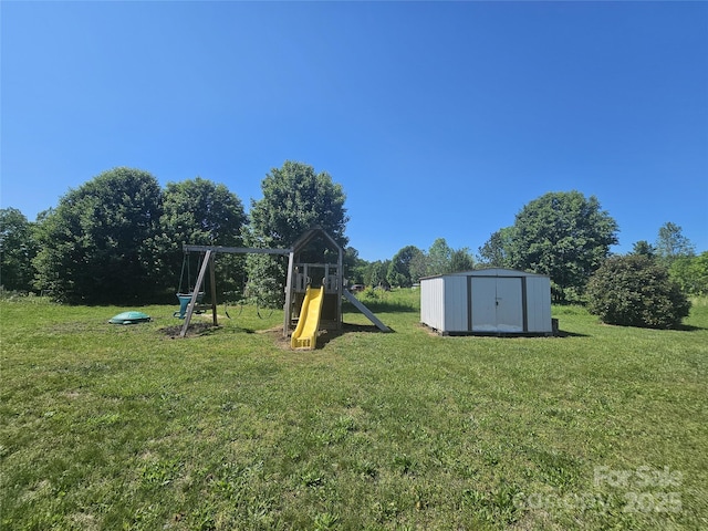 view of playground featuring a storage shed, a lawn, and an outbuilding