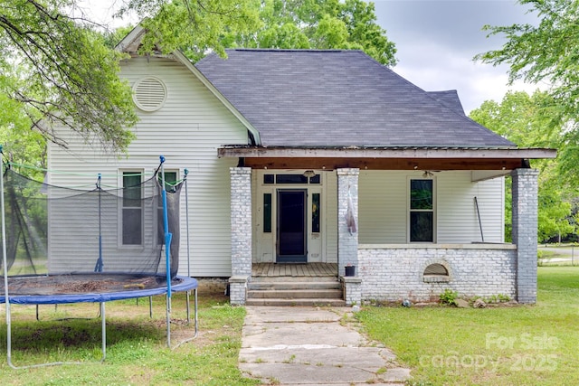 302 Charlotte St, York, SC 29745 - view of front of property with covered porch, a front lawn, roof with shingles, and a trampoline