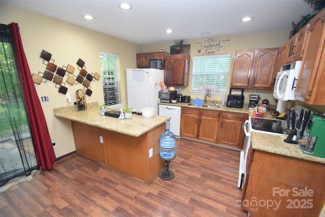 kitchen with a peninsula, white appliances, recessed lighting, and dark wood finished floors