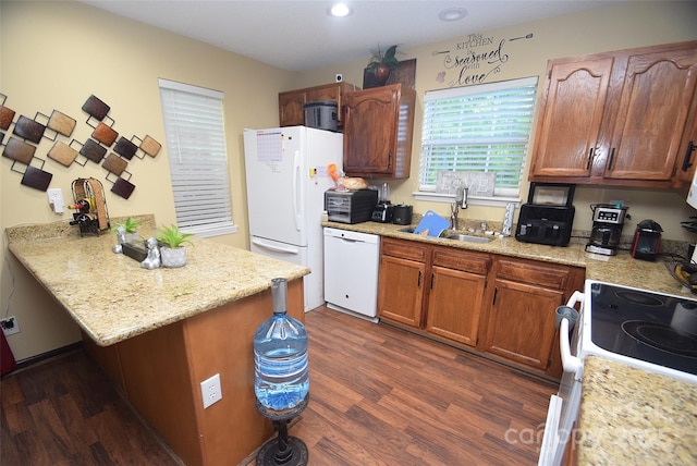 kitchen with a peninsula, dark wood-style floors, a sink, and white appliances