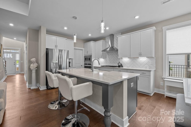1548 Striped Bass Ln, Clover, SC 29710 - kitchen featuring a breakfast bar area, appliances with stainless steel finishes, tasteful backsplash, baseboards, and wall chimney exhaust hood