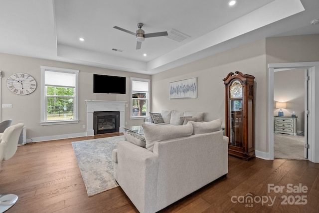 1548 Striped Bass Ln, Clover, SC 29710 - living room featuring ceiling fan, dark wood finished floors, a glass covered fireplace, baseboards, and a tray ceiling