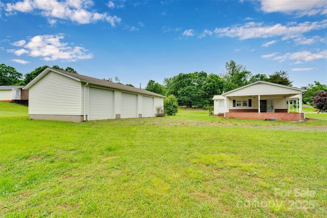 543 18th St NW, Hickory, NC 28601 - view of green lawn with a detached garage, a porch, and an outdoor structure