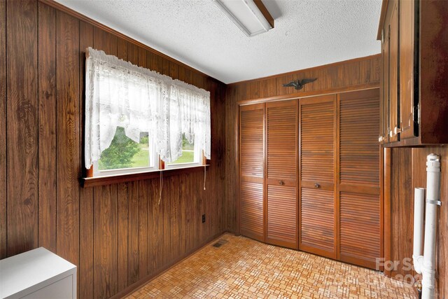 543 18th St NW, Hickory, NC 28601 - unfurnished bedroom featuring wood walls, a closet, and a textured ceiling