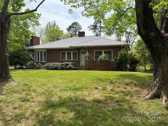ranch-style house with brick siding, a front lawn, a chimney, and metal roof