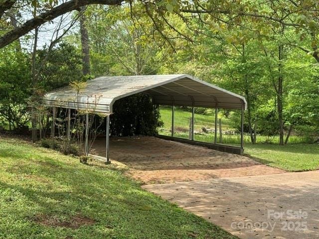 view of parking featuring a view of trees, a detached carport, and driveway