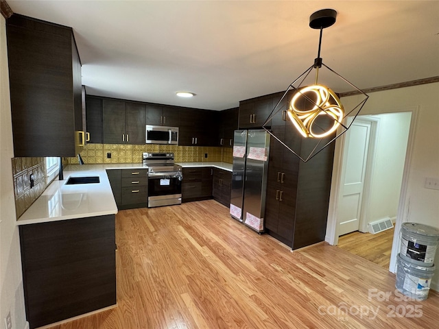 kitchen featuring light wood finished floors, light countertops, appliances with stainless steel finishes, and tasteful backsplash