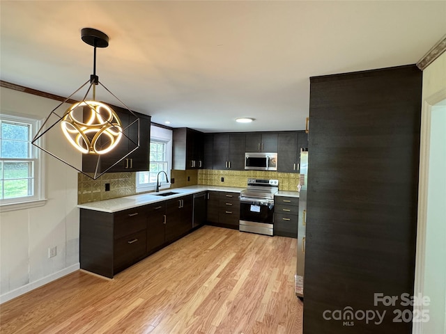 kitchen with light countertops, light wood-style flooring, stainless steel appliances, and a sink
