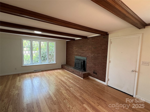 unfurnished living room featuring beamed ceiling, wood finished floors, visible vents, and baseboards