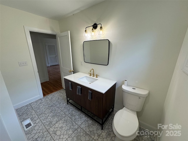 half bathroom featuring vanity, toilet, baseboards, and tile patterned floors