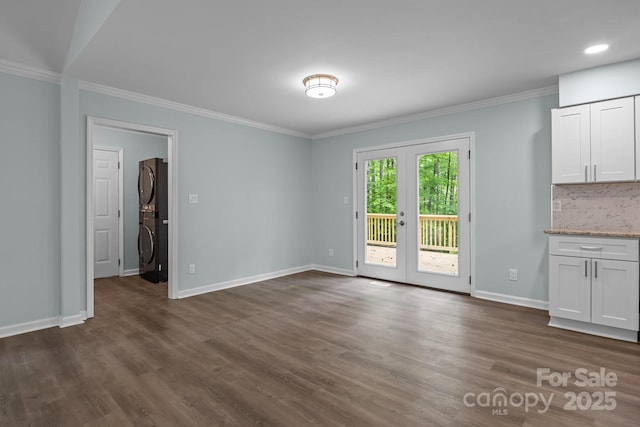 unfurnished dining area with stacked washer / drying machine, french doors, dark wood-style floors, and crown molding